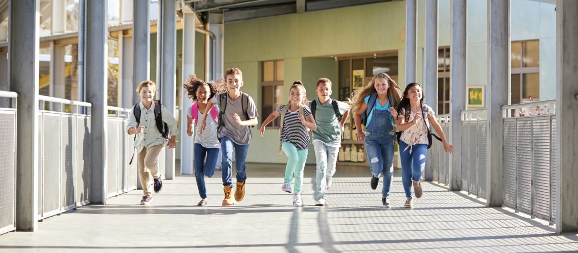 Group of elementary school kids running in a school corridor
